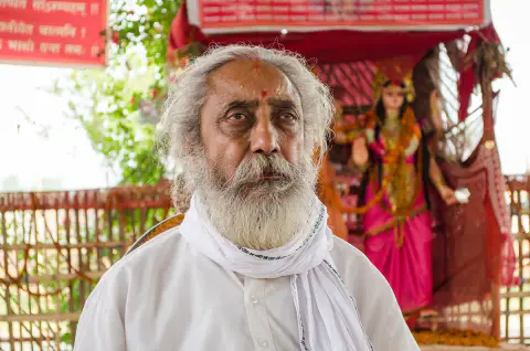 Portrait of Nepali Baba standing before images of the goddesses