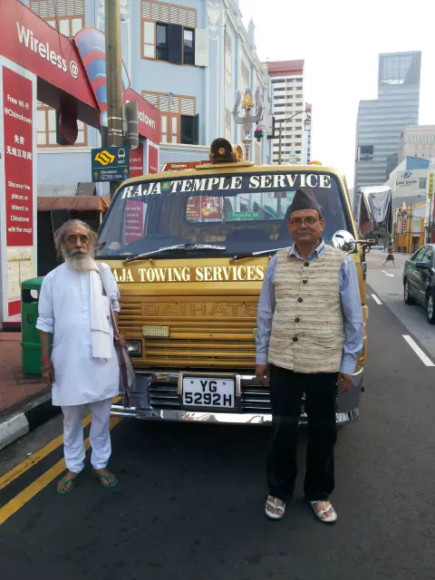 Nepali Baba and a companion standing beside a vehicle while travelling