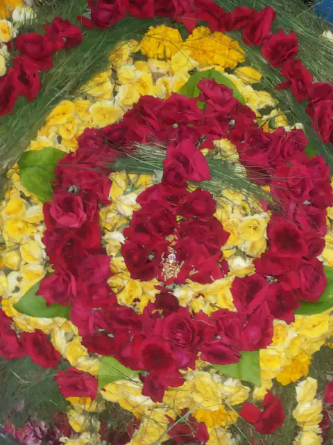 A circular devotional arrangement of red and yellow flowers