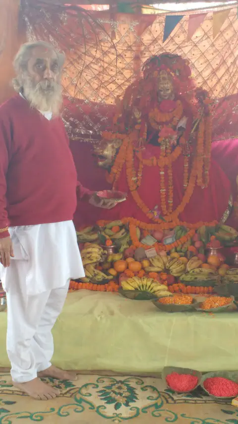 Nepali Baba standing beside a richly decorated image of the goddess